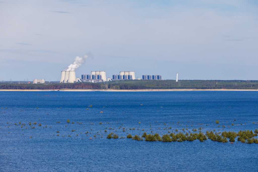 Kraftwerk mit Kühltürmen und rauchenden Schornsteinen, sichtbar über dem Cottbuser Ostsee